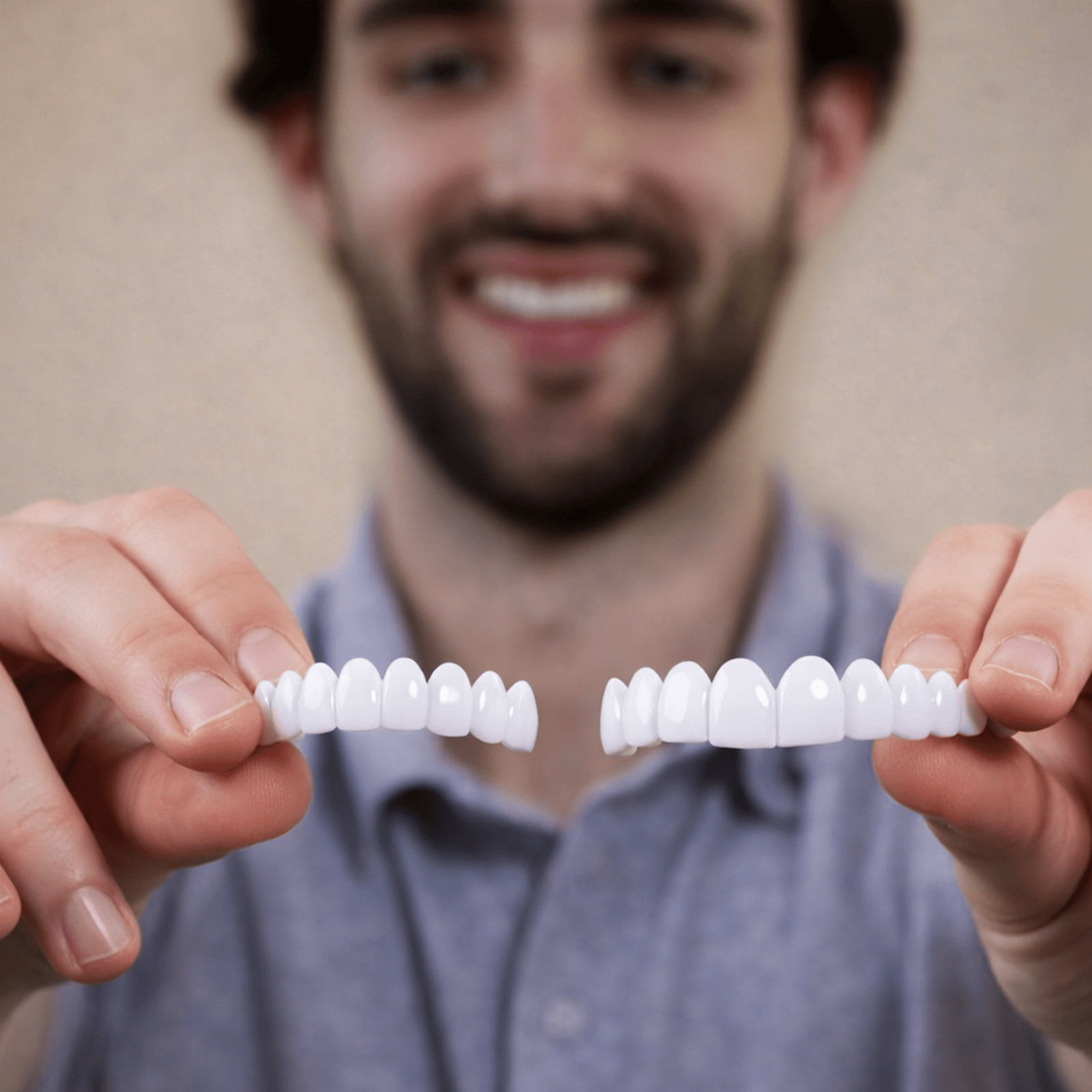 Man holding two sets of Pop On Veneers against a neutral background